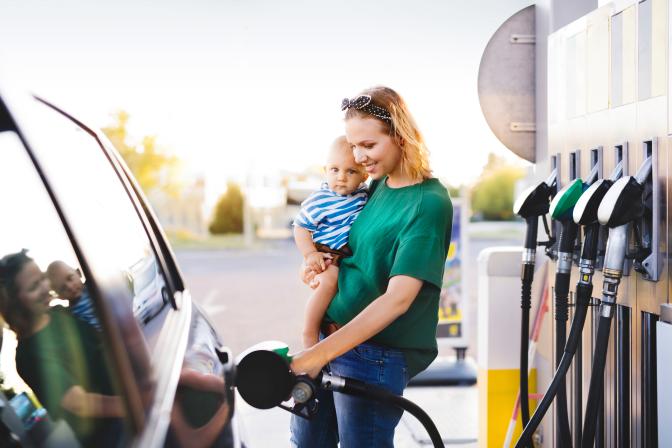 Junge Mutter mit Baby-Junge an der Tankstelle