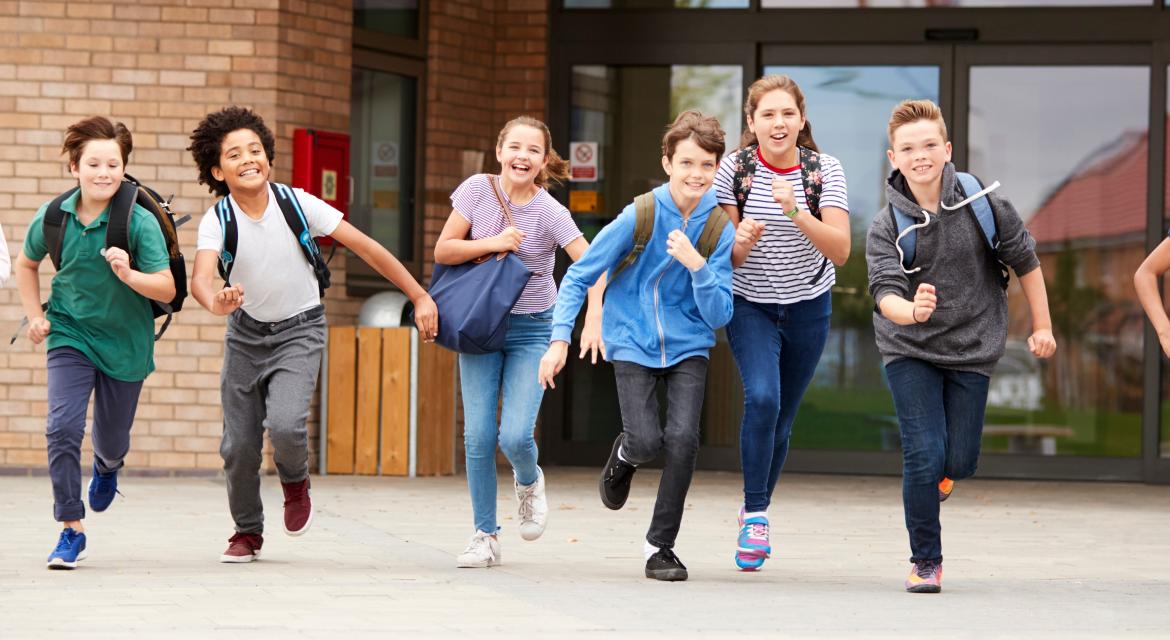 Rennende Schulkinder vor einer Schule